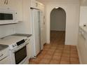 White kitchen with stainless steel appliances and terracotta floor at 144 Garden Ln, Sarasota, FL 34242