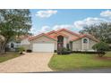 Tan house with orange roof, white garage door, and landscaped lawn at 5296 White Sand Ne Cir, St Petersburg, FL 33703