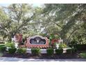 Beautifully landscaped community entrance sign amidst lush greenery and mature trees at 4174 Central Sarasota Pkwy # 214, Sarasota, FL 34238