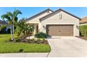 Tan house with brown garage door, landscaping, and palm trees at 12640 Coastal Breeze Way, Bradenton, FL 34211