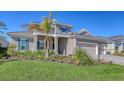 Two-story house with gray siding, three-car garage, and landscaping at 21205 Holmes Cir, Venice, FL 34293