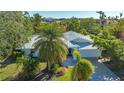 An eye-level view of a single-story home with a metal roof, lush landscaping, and a paved driveway at 435 Partridge Cir, Sarasota, FL 34236