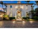 Stunning home with a grand entrance and beautiful landscaping at dusk at 65 Lighthouse Point Dr, Longboat Key, FL 34228