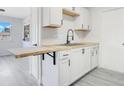 Renovated kitchen featuring white cabinets and a butcher block breakfast bar at 7555 Hanchey St, North Port, FL 34287