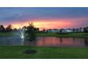 Aerial view of a community with lake, fountain, and houses at sunset at 16721 Barnwood Pl, Bradenton, FL 34211