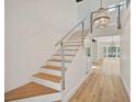 Elegant staircase featuring modern cable railing, hardwood steps, and a stylish chandelier at 5373 Dominica Cir, Sarasota, FL 34233