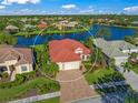 Single-story home with red tile roof, situated on a lake in a community at 521 Luminary Blvd, Osprey, FL 34229