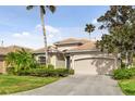 Tan one-story house with a two-car garage and palm trees at 9143 Willow Brook Dr, Sarasota, FL 34238