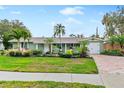 Green house with landscaped yard, brick driveway, and attached garage at 6623 Glades Way, Sarasota, FL 34231