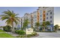 Beautiful condo building featuring a branded sign, palm trees, well-maintained landscaping, and colorful facade at 505 Tamiami N Trl # 201, Venice, FL 34285