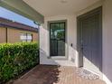 Front entry with gray door, brick flooring, and a small window at 2479 Brassica Dr, North Port, FL 34289