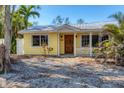 Front view of a yellow house with a porch and mature trees at 563 Juan Anasco Dr, Longboat Key, FL 34228
