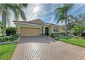 One-story house featuring a tan exterior, palm trees, and a brick driveway at 8912 Heritage Sound Dr, Bradenton, FL 34212