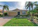 One-story home with a tan exterior, lush landscaping, and a brick driveway at 8912 Heritage Sound Dr, Bradenton, FL 34212