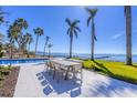 Waterfront patio features a dining area with a modern table and chairs, a pool, and stunning ocean views at 4311 Bay Shore Rd, Sarasota, FL 34234