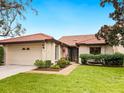Front view of a tan villa with a brown tile roof and lush landscaping at 7323 Oak Moss Dr # 42, Sarasota, FL 34241