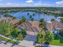 Aerial view of a house with a lake view, private pool and a tile roof, surrounded by palm trees at 518 Luminary Blvd, Osprey, FL 34229