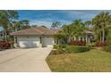 House exterior featuring a three-car garage and lush landscaping at 1965 White Feather Ln, Nokomis, FL 34275