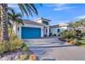 Striking single-story home featuring a vivid blue garage door, lush landscaping, and a paved driveway at 4779 Pastel Ct, Sarasota, FL 34240