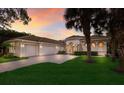 Stunning home exterior with a three-car garage, tile roof, and lush landscaping under a colorful sunset at 3769 Caledonia Ln, Sarasota, FL 34240