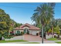 Charming single-Gathering home with a clay tile roof, tropical landscaping, a paved driveway, and a two-car garage at 4946 Brywill Cir, Sarasota, FL 34234