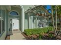 Front entrance with white door, arched window, and manicured hedges at 6523 Virginia Xing, University Park, FL 34201
