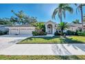 Beautiful home exterior with landscaping, three car garage, and palm trees at 8365 Shadow Pine Way, Sarasota, FL 34238