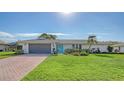 Single-story house with teal front door and brick paver driveway at 4842 Greywood Ln, Sarasota, FL 34235