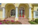 Front entrance with a red door, white columns, and brick flooring at 8205 Quail Greens Ter, Bradenton, FL 34212