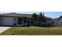 House with a gray exterior, palm trees, and a fenced backyard at 9359 Casa Grande Ave, Englewood, FL 34224