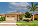 Tan house with beige garage door, landscaping, and paver driveway at 11786 Sistine Ln, Venice, FL 34293