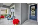Inviting front porch with blue chairs, red flowers, and a navy blue front door at 12117 Whisper Lake Dr, Bradenton, FL 34211