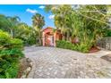 Charming light pink home with lush tropical landscaping and a brick driveway at 235 Grant Dr, Sarasota, FL 34236