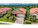 Single-Gathering home with a red tile roof and a paved driveway, situated in a community with a pond at 23463 Copperleaf Dr, Venice, FL 34293