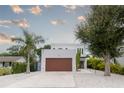 White two-story house with wood garage door and landscaping at 5906 Larchwood Ave, Sarasota, FL 34231