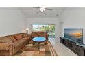 Spacious living room with a brown sofa, large TV, and sliding doors to balcony at 7107 Cedar Hollow Cir, Bradenton, FL 34203
