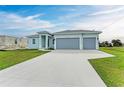 Newly built home with light blue exterior, three-car garage and large driveway at 75 Mark Twain Ln, Rotonda West, FL 33947