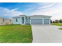 Newly built home with light blue exterior, three car garage and spacious lawn at 75 Mark Twain Ln, Rotonda West, FL 33947