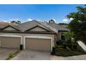 Three-car garage villa with dark brown tile roof, next to a lake at 8199 Varenna Dr, Sarasota, FL 34231