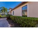 Landscaped walkway beside a tan home with large windows at 8224 Varenna Dr, Sarasota, FL 34231