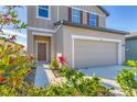 Two-story house with neutral siding, two-car garage, and landscaped yard at 10611 Ladybug Cv, Parrish, FL 34219