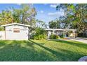Ranch-style home with lush green lawn and mature trees at 1100 27Th W Ave, Palmetto, FL 34221
