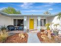 Inviting front porch with yellow door, brick walkway, and potted plants at 2708 Bigelow Dr, Sarasota, FL 34239