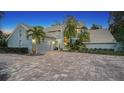 Two-story house with gray brick exterior, palm trees, and a paver driveway at 4892 Peregrine E Pt, Sarasota, FL 34231