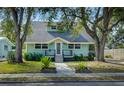 Quaint light teal house with a grey roof, walkway, and mature trees at 1213 5Th W St, Palmetto, FL 34221