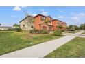 Two-story townhome with orange exterior, two-car garage, and landscaped yard at 20447 Lagente Cir, Venice, FL 34293
