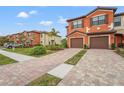Two-story townhome with orange exterior, two-car garage, and landscaped yard at 20447 Lagente Cir, Venice, FL 34293