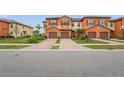 Townhome with orange exterior, three-car garage, and manicured lawn at 20447 Lagente Cir, Venice, FL 34293