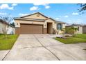 One-story house with brown garage door, gray door, and landscaped yard at 7308 Tangle Bend Dr, Gibsonton, FL 33534
