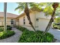 Side view of home showcasing a tan stucco exterior, lush landscaping, and a decorative gate at 3416 W Chelmsford Ct # 2, Sarasota, FL 34235